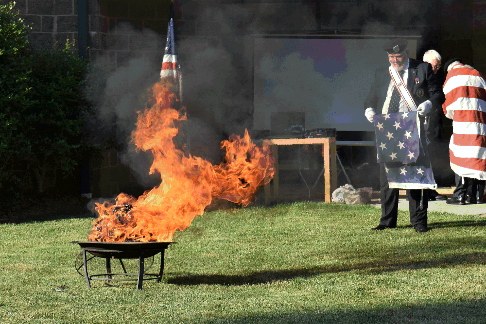 Worthy Navigator Eddie Williams prepares a section of the a flag for the respectful burning.